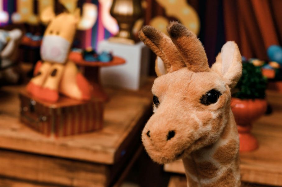 Giraffe plush toy with other toys in the background. 