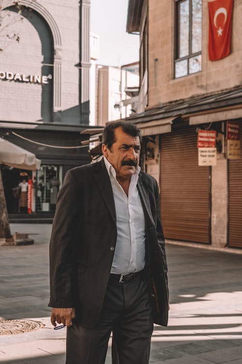 A man in a black blazer standing on the street side