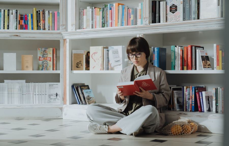 a person sitting on the floor while reading a book