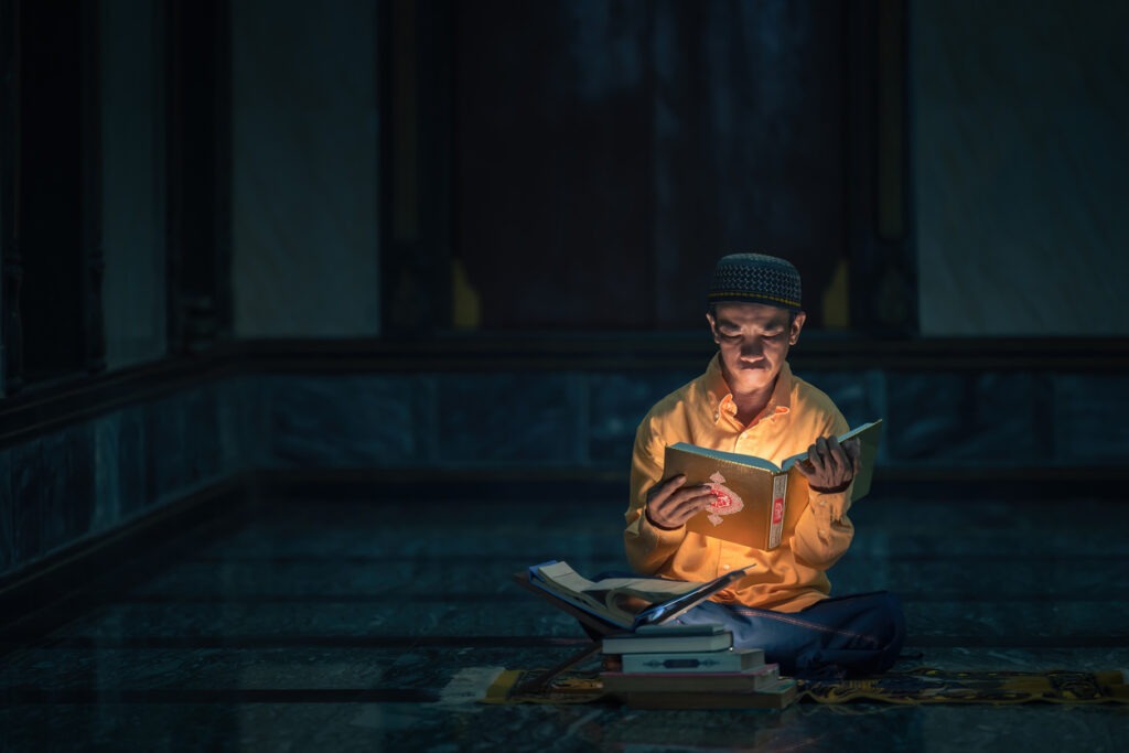 a man reading a glowing book in a darkened room